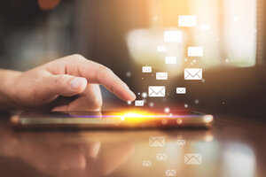 Frauenhand mit Smartphone im Hintergrund fliegende E-Mail-Symbole 