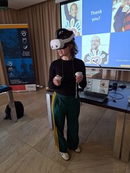 Teilnehmer mit VR-Brille vor einem Präsentationsbildschirm